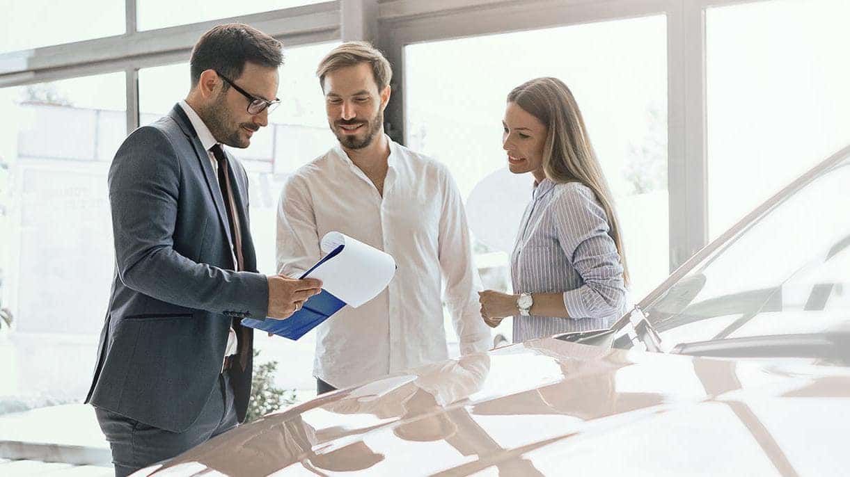 Couple with salesman discussing leasing options 