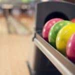 Pink, yellow, and green bowling balls lined up
