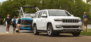 The 2022 Jeep Wagoneer towing a boat next to people getting out of the water.