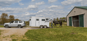 The all-new 2022 Jeep Grand Wagoneer towing a horse carrier from a farm.