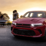Angled photo of 2024 Dodge Hornet parked in front of a park with people meeting behind it