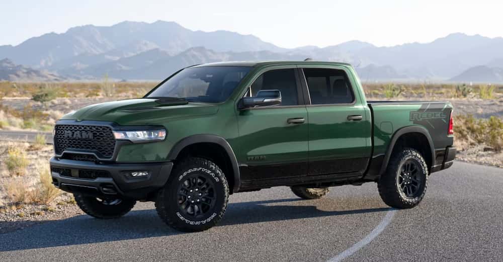 A dark green 2026 RAM 1500 pickup truck parked across a desert road