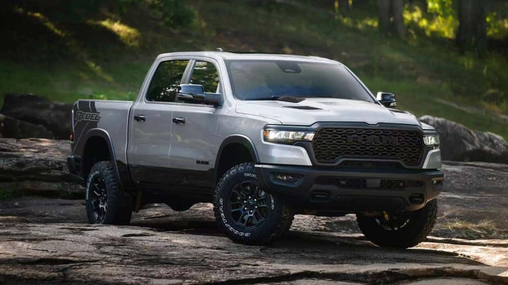 A silver 2026 Ram 1500 Rebel pickup truck parked on a rocky outcropping
