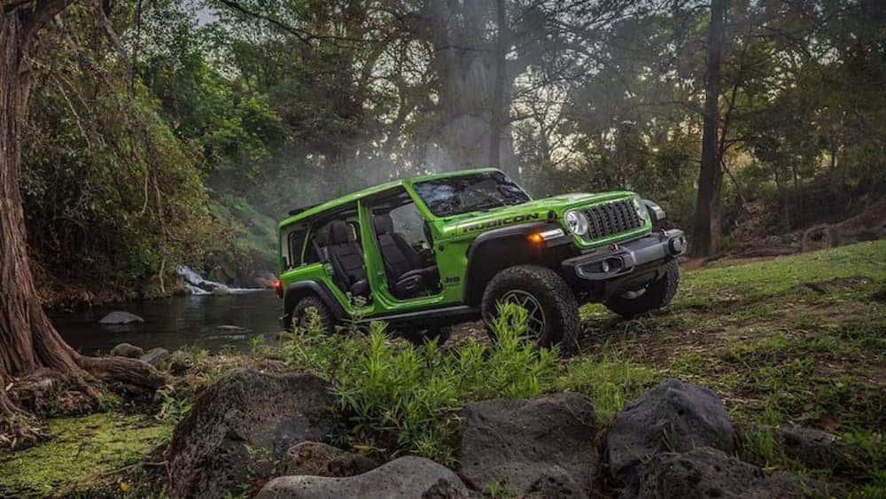A bright green 2026 Jeep Wrangler Rubicon parked on the edge of a stream