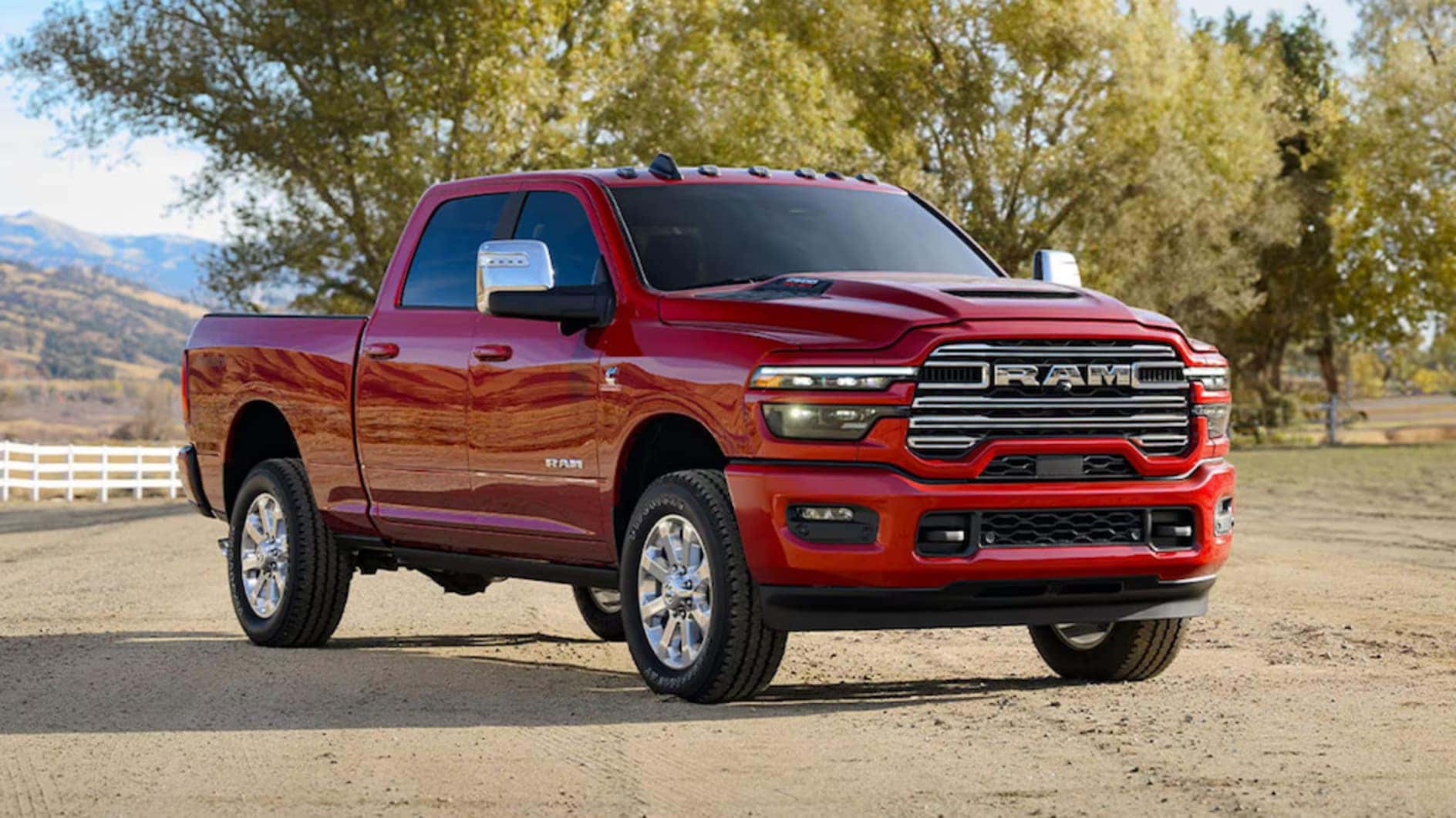 A red 2026 Ram 2500 pickup truck parked in front of trees and dry hills
