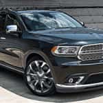 Black Dodge Durango SUV parked at an angle, reflecting sunlight on its polished exterior, with a metallic grille and chrome accents.