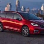 sideview of red chrysler pacficia van parked with city skyscape in background