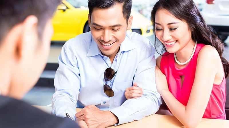 Couple signing sales contract for car at dealership 