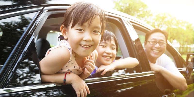 happy little girl with family sitting in the car