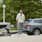 2019 Buick Enclave towing a boat as child runs toward it