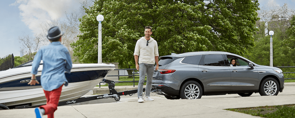 2019 Buick Enclave remolcando un barco de niño corre hacia él