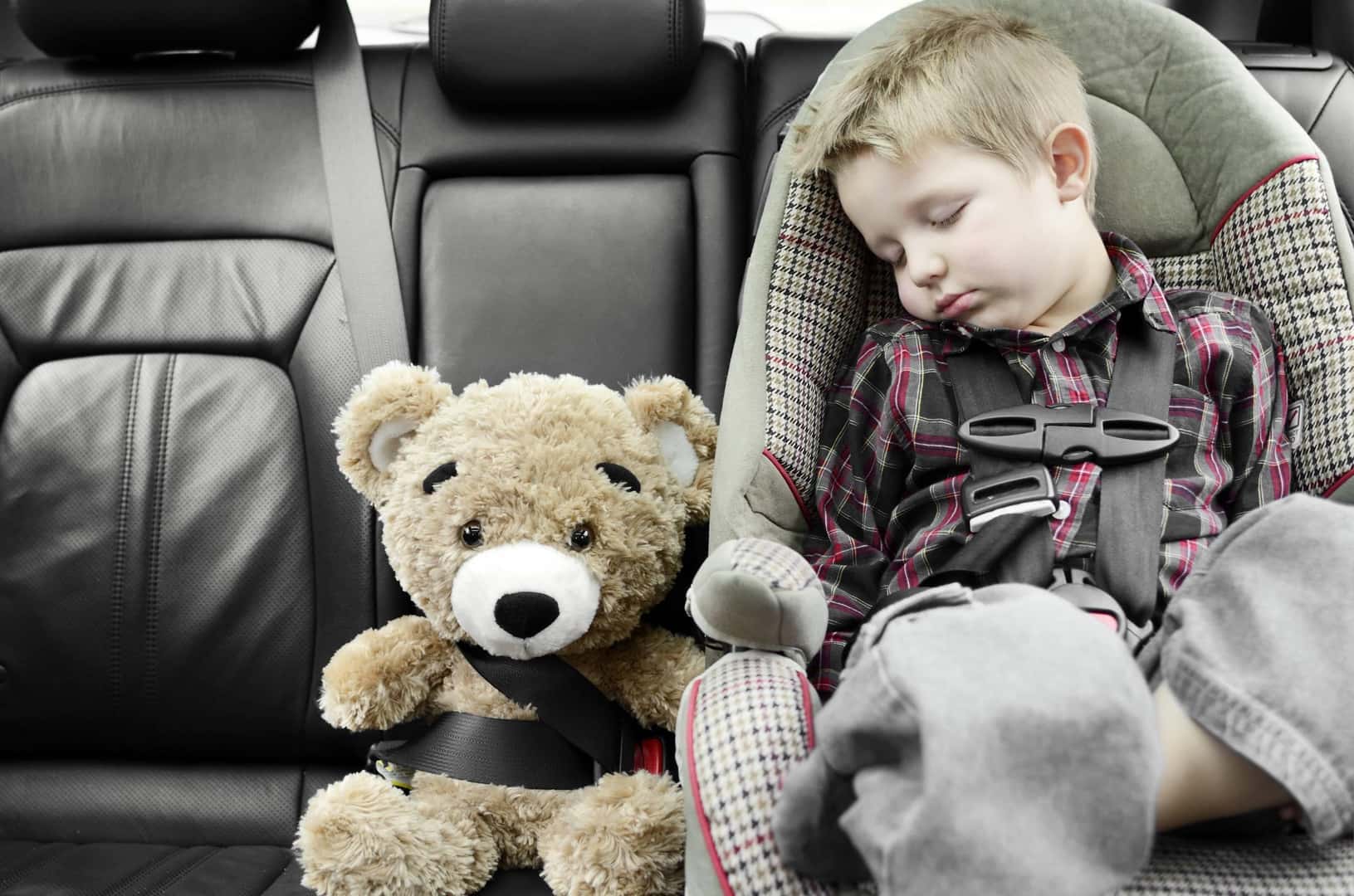 Child asleep in car seat next to teddy bear, car-seat safety