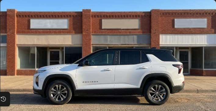 Chevrolet Equinox parked on a small-town Main Street near a local Oklahoma credit union branch, Carter Chevrolet finance folder on the hood