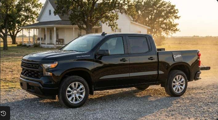 Black Chevrolet Silverado 1500 on a rural Oklahoma driveway at golden hour with a Carter Chevrolet finance folder on the tailgate