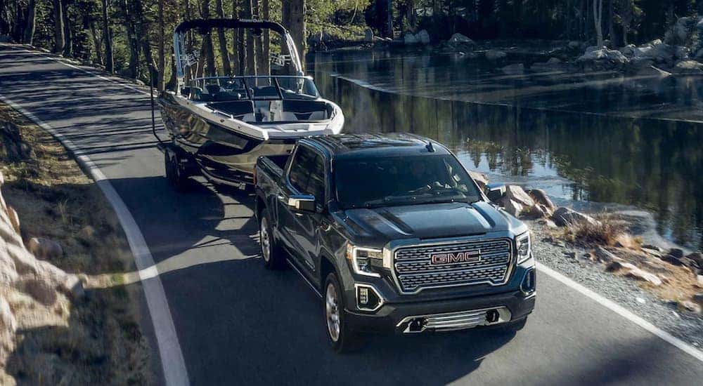 A grey 2022 GMC Sierra 1500 Limited is shown towing a fishing boat near a small lake.