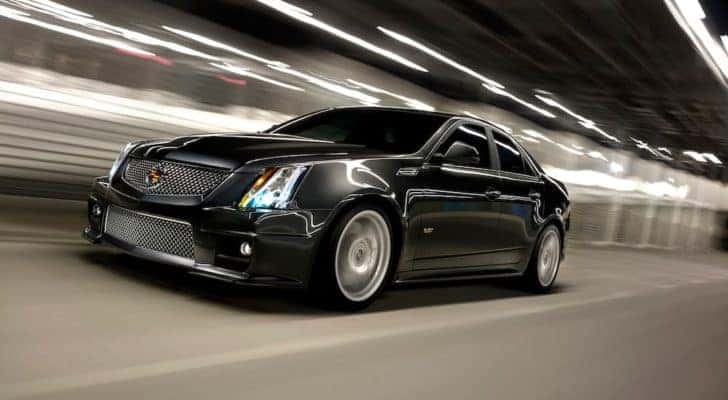 A popular used Cadillac in Chesapeake, VA, a black 2014 Cadillac CTS-V, is shown driving through a tunnel.