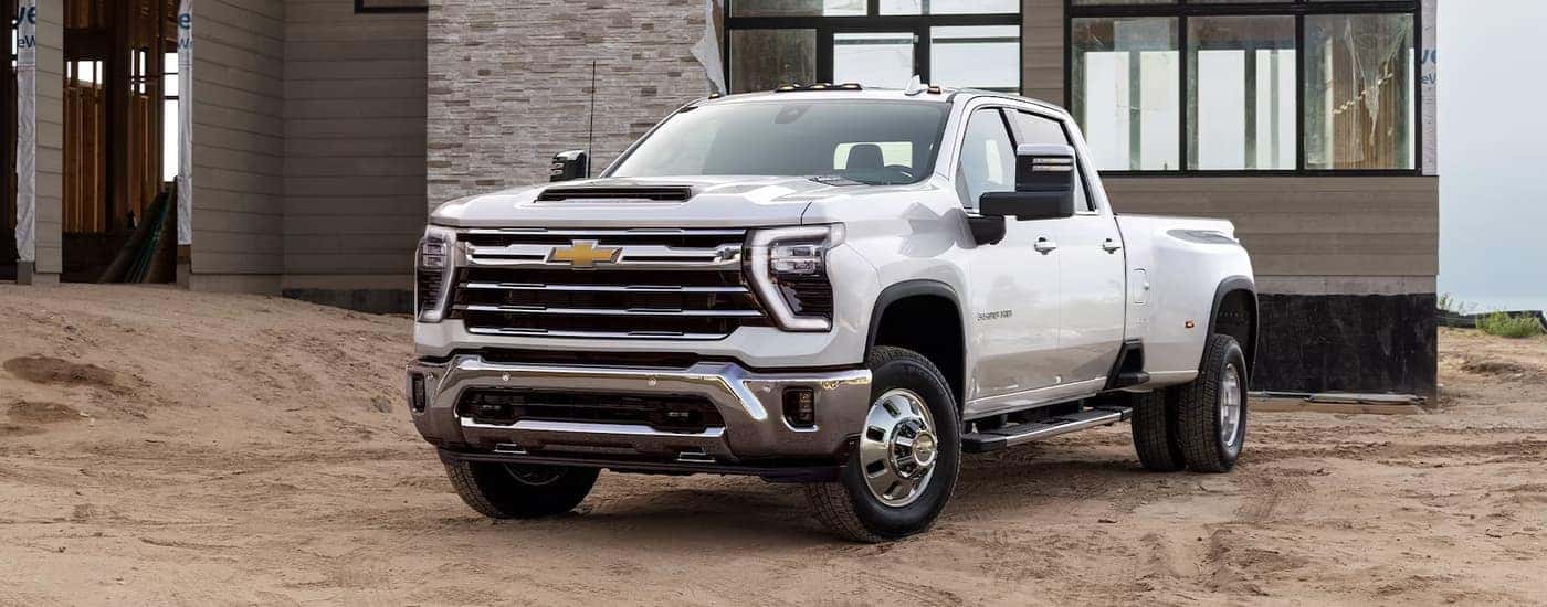 A white 2024 Chevy Silverado 2500HD is shown parked at a construction site.