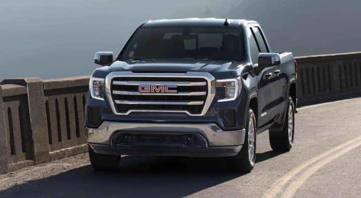 A blue 2022 GMC Sierra 1500 is shown driving on an open road.