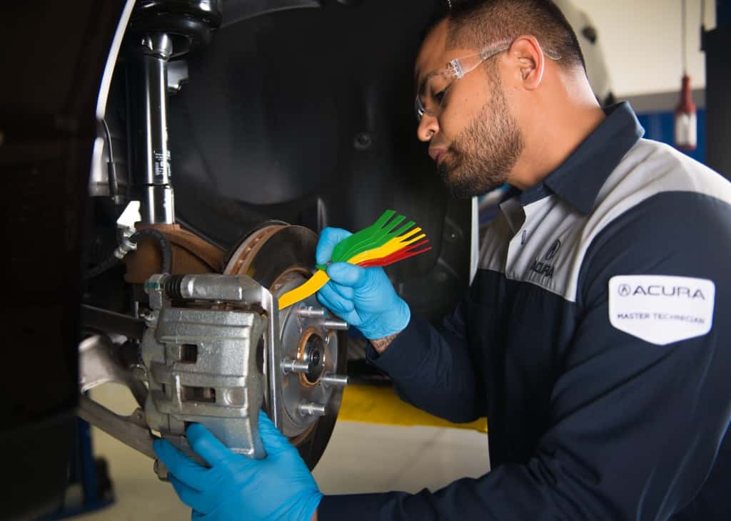 Acura service technicial performing brake inspection and maintenance