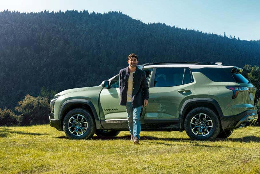 2025 Chevrolet Equinox ACTIV parked outdoors with driver beside the vehicle in a scenic mountain setting