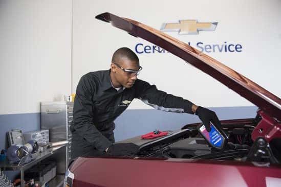 Certified Chevrolet technician performing winter maintenance under the hood at Greg Hubler Chevrolet service center