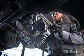 Chevy service technician inspecting the underside of a vehicle during battery maintenance at Greg Hubler Chevrolet Camby IN