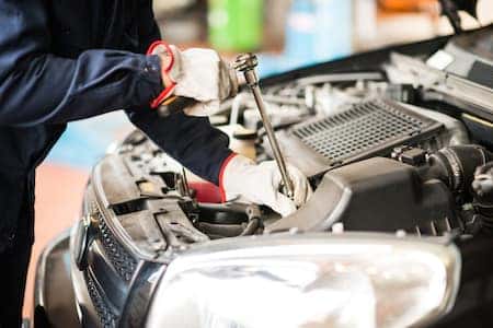 Technician utilizing tool to fix vehicle parts