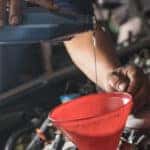 Male adding oil with a funnel