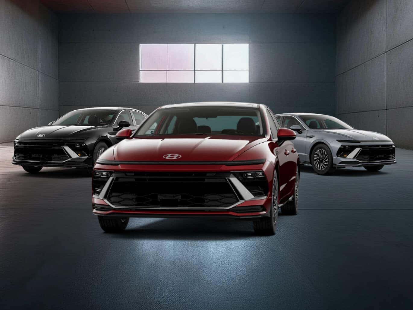 Three 2026 Hyundai Sonata models, one black, one red, one silver, parked side by side in a dark warehouse.