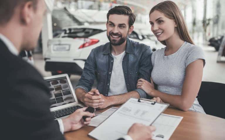 Couple talking things over with a sales representative at a desk in the showroom