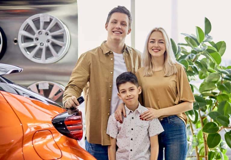Family standing next to new car purchase