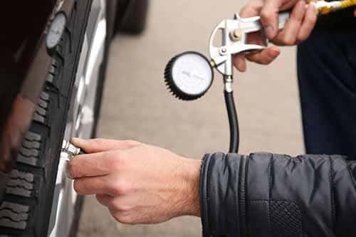 Auto mechanic checking tire pressure