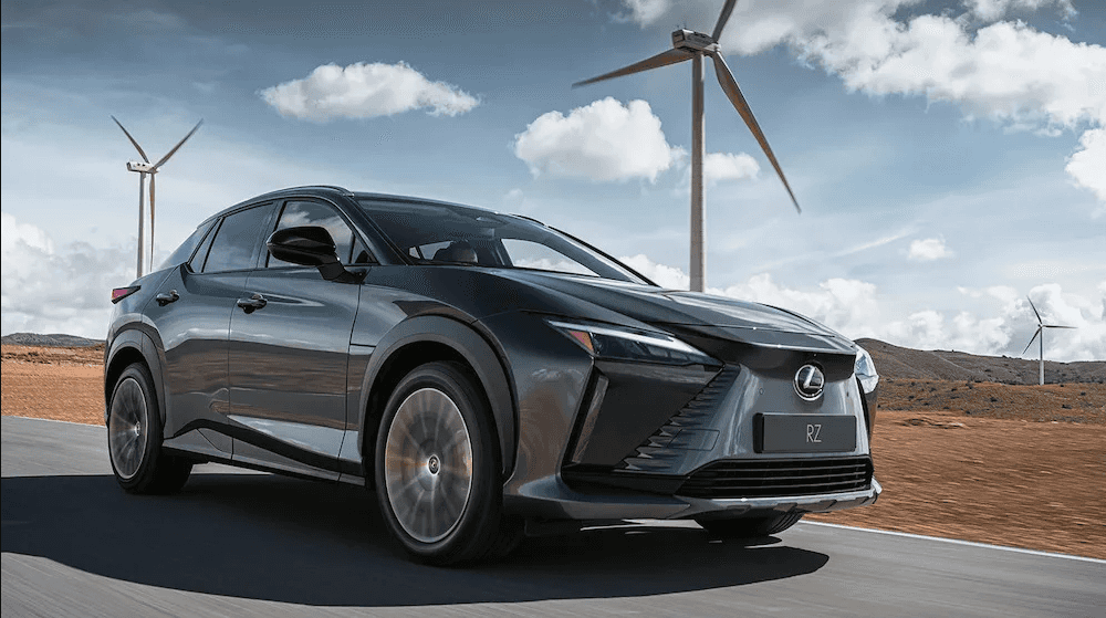 Lexus RZ 450e driving past wind turbines and hills in the distance