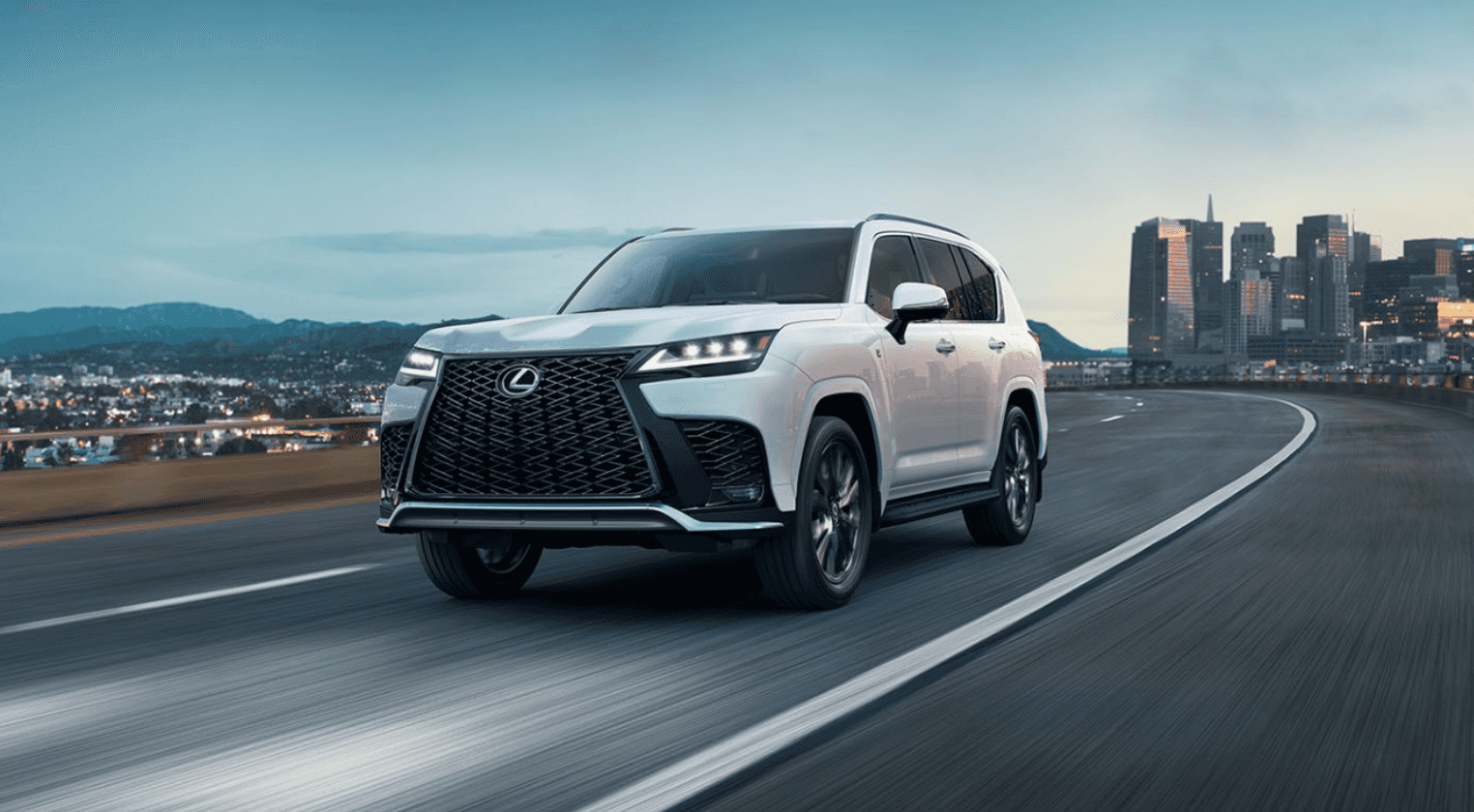 2024 Lexus LX driving with a cityscape in the background