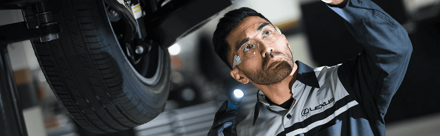 A Lexus service technician performing service under a vehicle