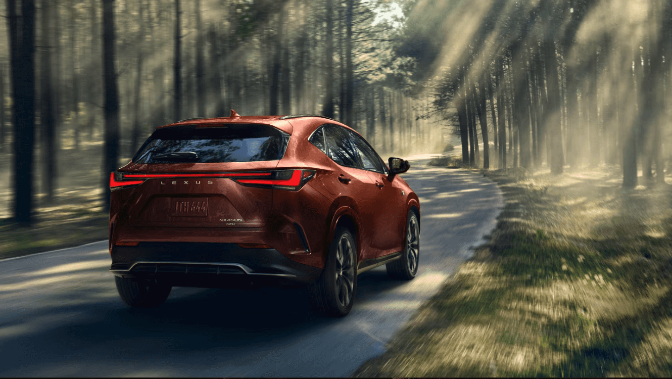 Rear view of the 2025 Lexus NX Plug-in Hybrid driving through a forest