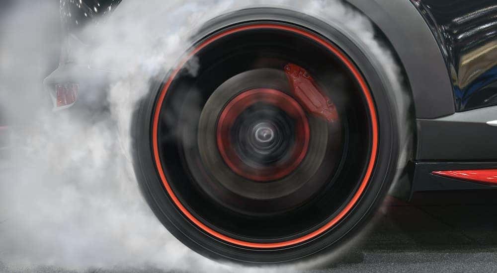 A tire doing a burn out is shown in close up.