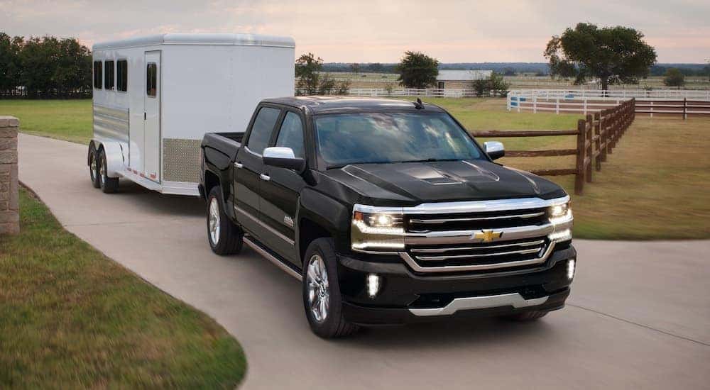 A black 2018 Chevy Silverado 1500 High Country is shown towing a white trailer after looking at used cars in Cincinnati, Ohio.