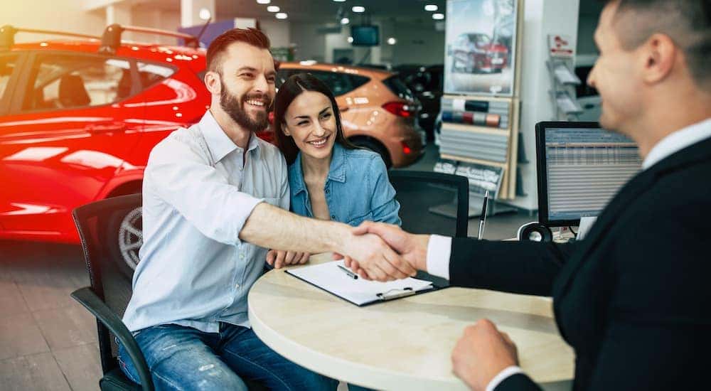 A couple is shown signing paperwork after searching 'sell your car.'