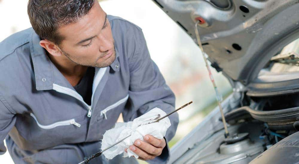 A person is shown checking the oil in a Cincinnati Ohio used car.
