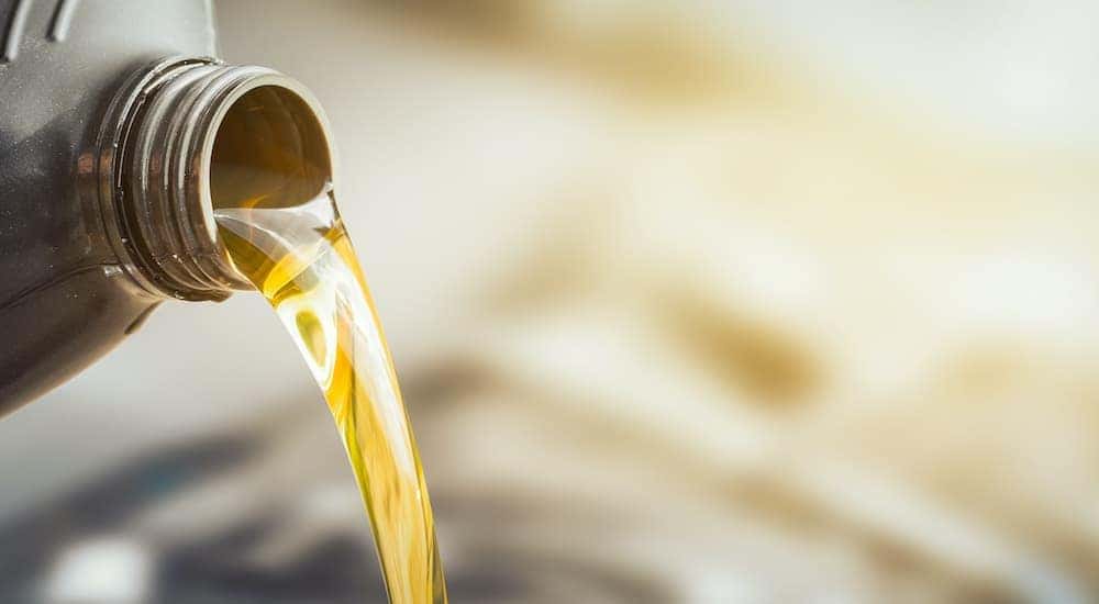 A bottle of oil is shown being poured into an engine.