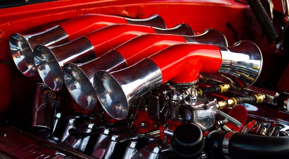 A closeup shows a high performance engine in a red car.