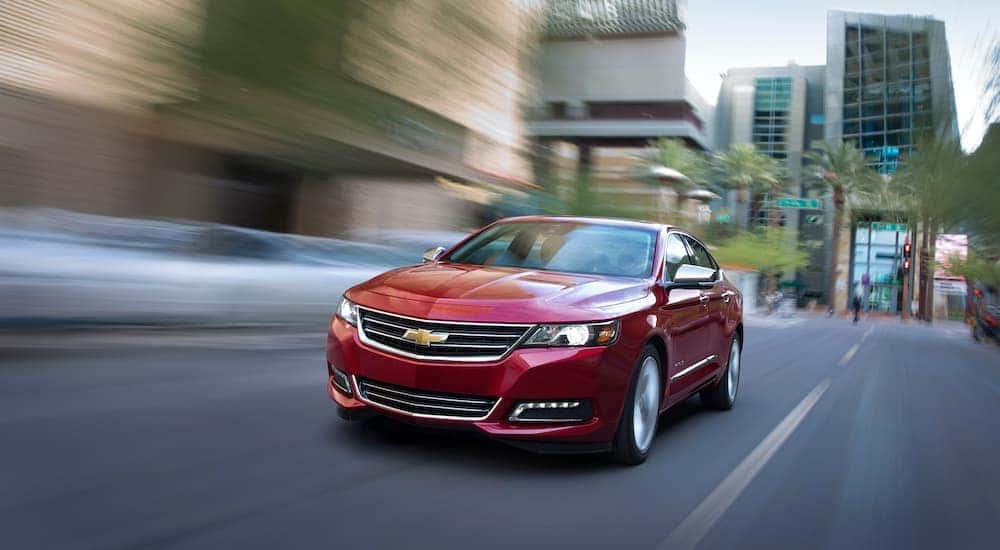 A red 2015 Chevrolet Impala is shown driving through a city.