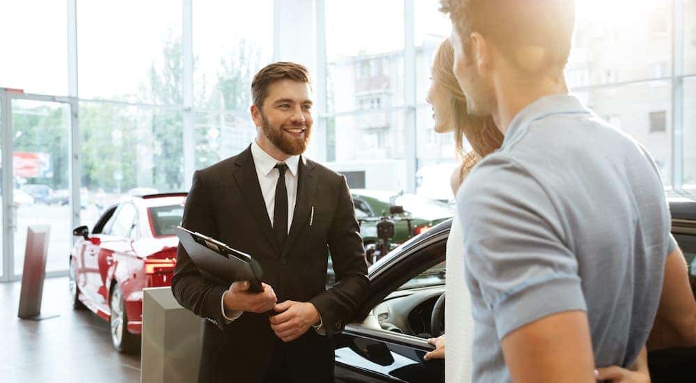 A couple is talking to a salesperson about bad credit car loans at a dealership.