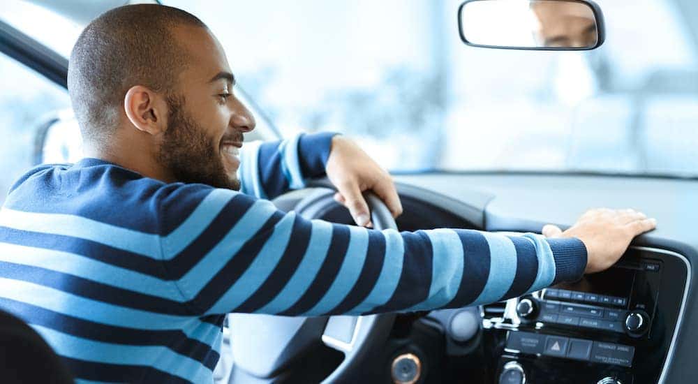 A man is shown sitting in the front seat of a car after searching "sell my car."