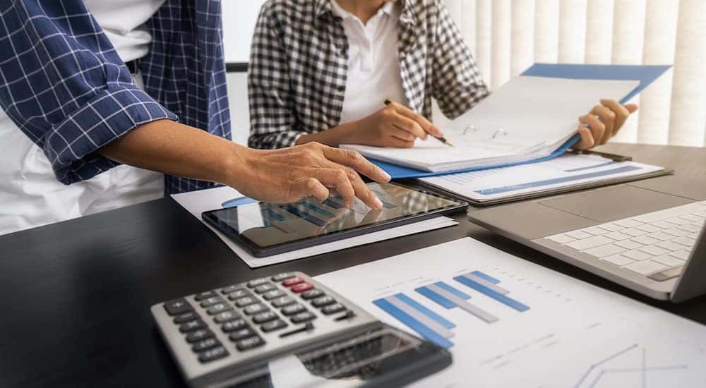 A man and woman are financing with a calculator and tablet.