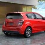Sell your car today, like this red 2018 Chevy Sonic Hatchback, that is parked in front of a modern home.