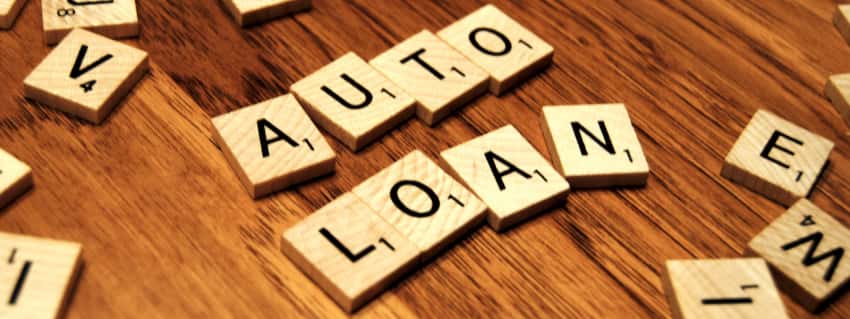 The words Auto Loan are spelled out in Scrabble letters on a table.