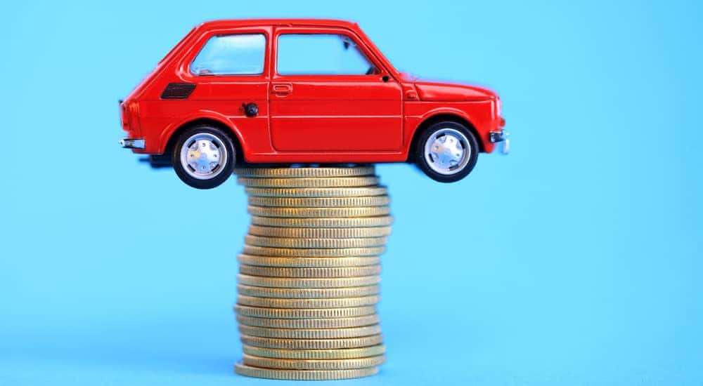Red toy cars on top of a stack of gold coins