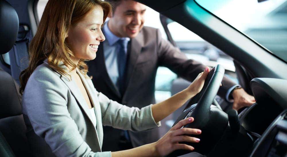 A woman is shown sitting in the front seat of a car at a buy here pay here in Dayton.